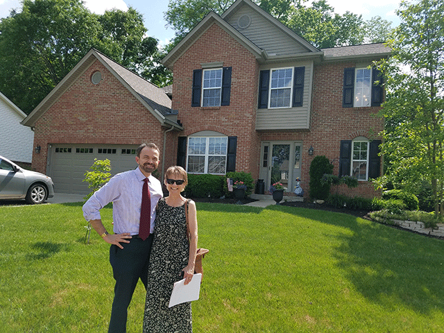 Couple in front of home with papers